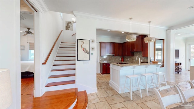 kitchen with ornamental molding, decorative backsplash, a ceiling fan, and stone tile floors