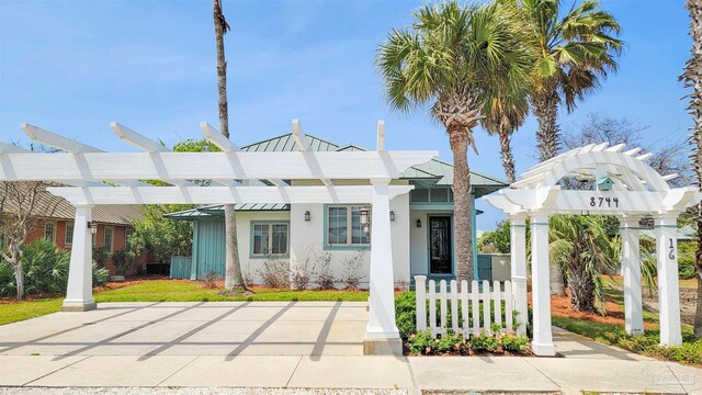 view of front of house featuring a pergola, a standing seam roof, metal roof, and stucco siding