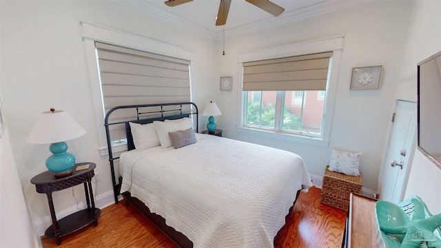 bedroom with ornamental molding, baseboards, ceiling fan, and wood finished floors