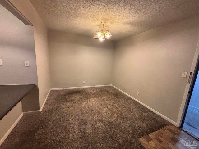 spare room with carpet floors, an inviting chandelier, baseboards, and a textured ceiling