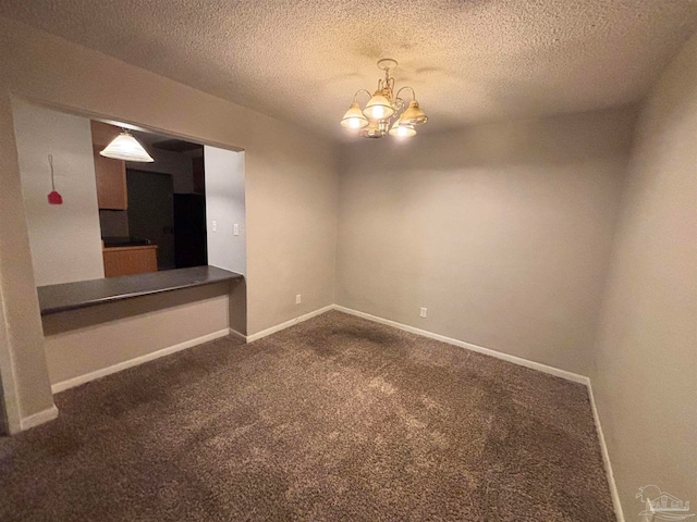 unfurnished room featuring a notable chandelier, dark carpet, and a textured ceiling