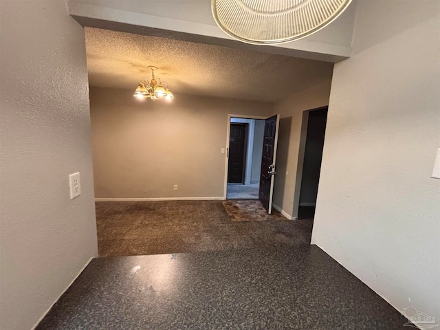 unfurnished room with a notable chandelier, baseboards, a textured ceiling, and a textured wall