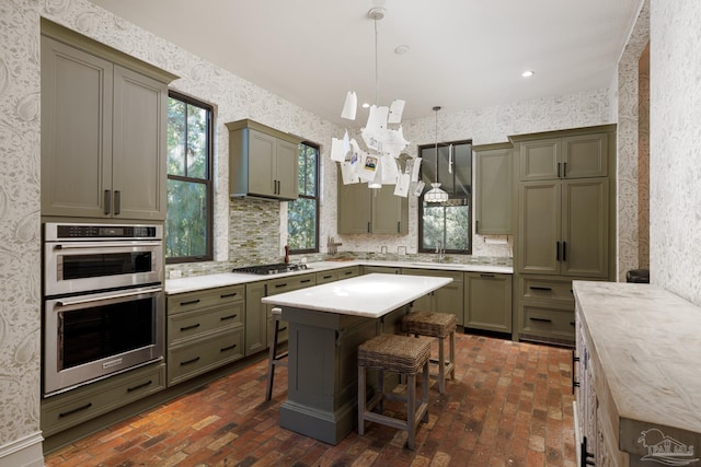 kitchen with stainless steel appliances, sink, a notable chandelier, hanging light fixtures, and a breakfast bar area