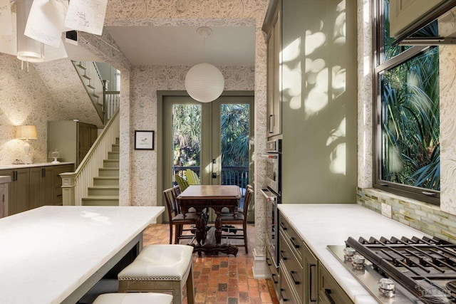 kitchen with decorative backsplash, pendant lighting, stainless steel appliances, and french doors