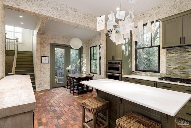 kitchen featuring pendant lighting, french doors, green cabinetry, appliances with stainless steel finishes, and tasteful backsplash