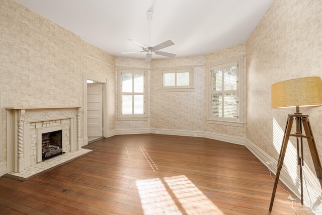 unfurnished living room with ceiling fan, a fireplace, and wood-type flooring