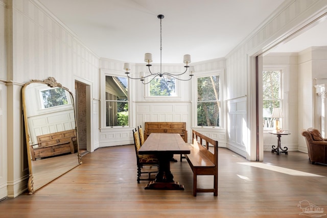 dining room with hardwood / wood-style flooring, crown molding, and an inviting chandelier