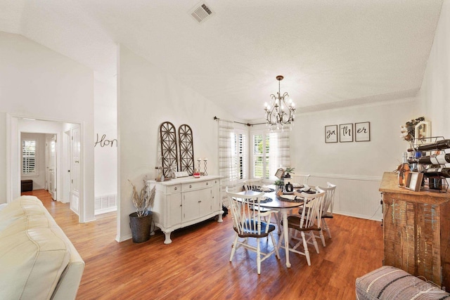 dining area featuring visible vents, vaulted ceiling, an inviting chandelier, and wood finished floors