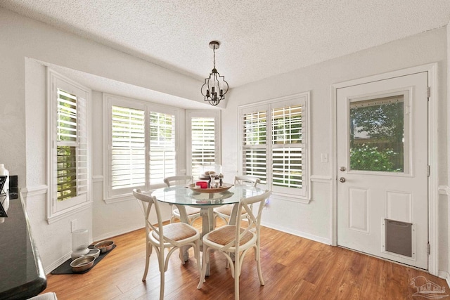 dining room with plenty of natural light, a textured ceiling, an inviting chandelier, and wood finished floors