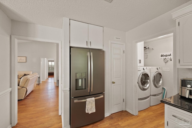 laundry room featuring washer and clothes dryer, visible vents, cabinet space, light wood-style flooring, and a textured ceiling