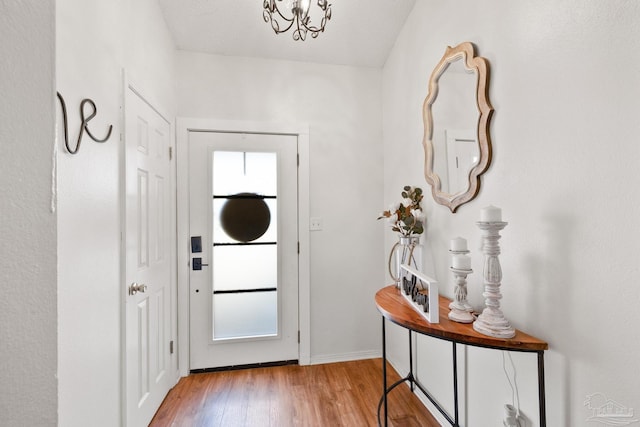 doorway with light wood-type flooring, baseboards, and a textured ceiling