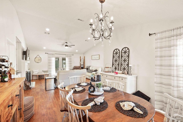 dining space featuring light wood-type flooring, ceiling fan with notable chandelier, visible vents, and lofted ceiling