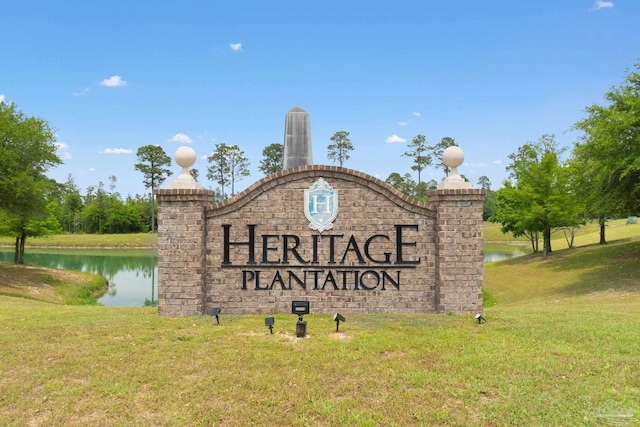 community sign featuring a lawn and a water view