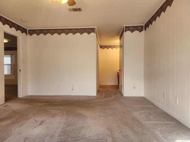 carpeted spare room with crown molding, ceiling fan, and a textured ceiling