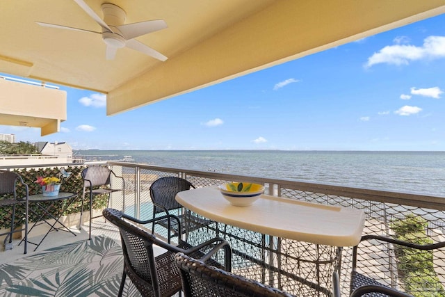 balcony with a view of the beach, a water view, and ceiling fan