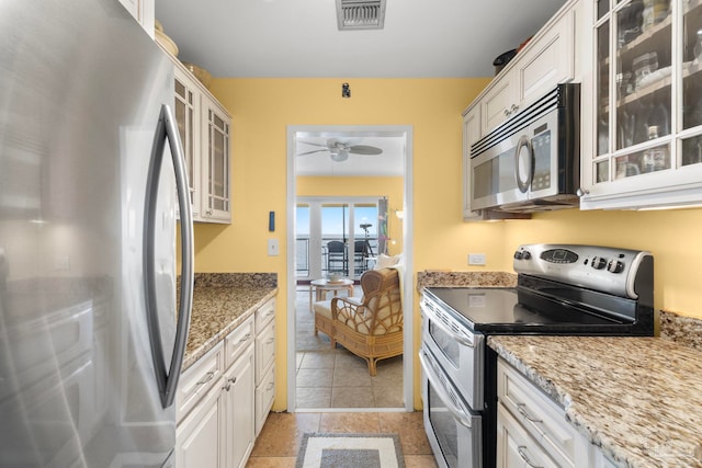 kitchen with light stone countertops, white cabinetry, and stainless steel appliances