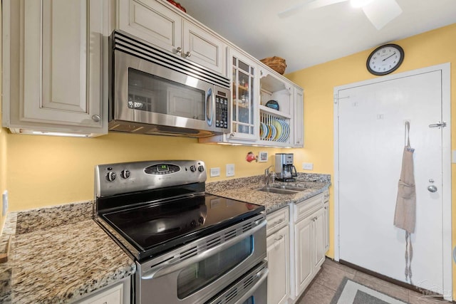 kitchen featuring stainless steel appliances, sink, light stone countertops, light tile patterned flooring, and white cabinetry