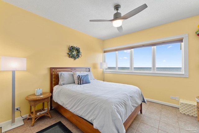 tiled bedroom with multiple windows, a textured ceiling, a water view, and ceiling fan