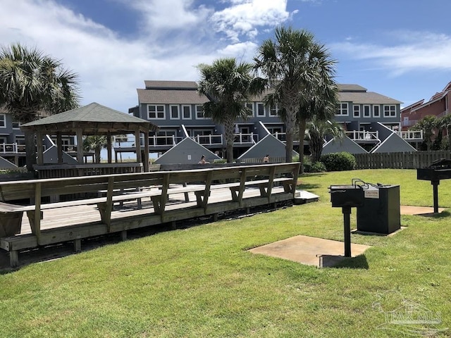 view of dock with a wooden deck, a gazebo, and a lawn