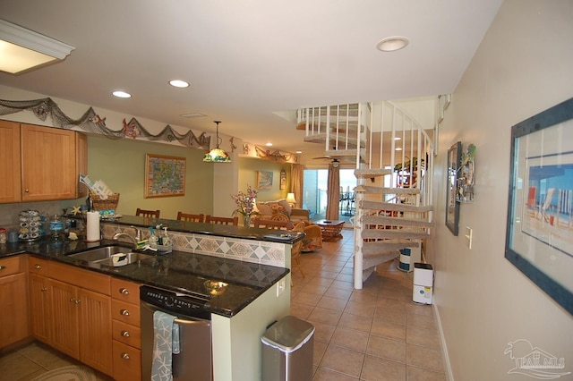 kitchen with light tile patterned floors, sink, dishwasher, kitchen peninsula, and dark stone counters