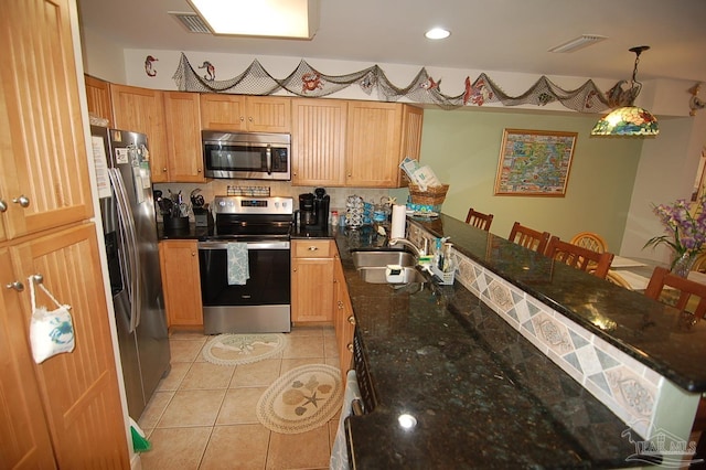 kitchen featuring light tile patterned flooring, appliances with stainless steel finishes, pendant lighting, sink, and dark stone counters