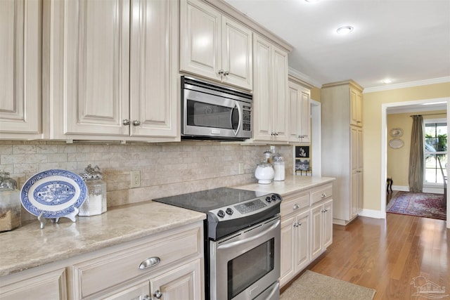 kitchen featuring crown molding, light wood-type flooring, baseboards, backsplash, and appliances with stainless steel finishes