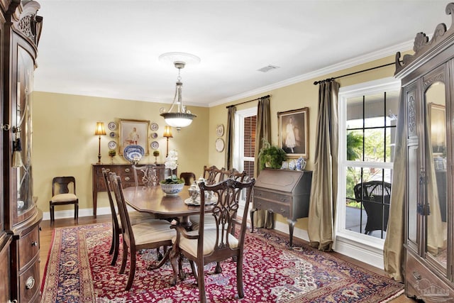 dining area featuring baseboards, ornamental molding, visible vents, and wood finished floors