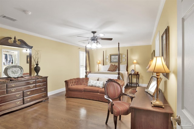 bedroom featuring wood finished floors, crown molding, baseboards, and visible vents