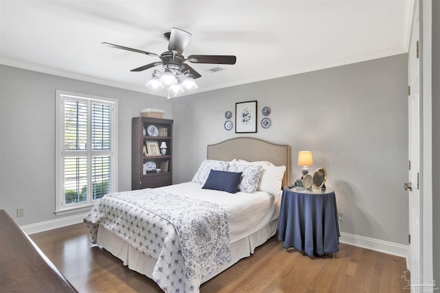 bedroom featuring ornamental molding, baseboards, visible vents, a ceiling fan, and wood finished floors
