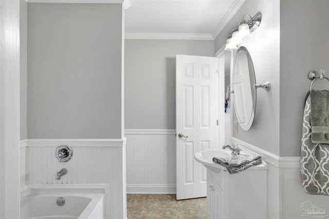 bathroom with tile patterned floors, crown molding, vanity, wainscoting, and a bath