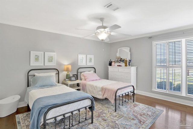 bedroom with baseboards, visible vents, crown molding, and wood finished floors