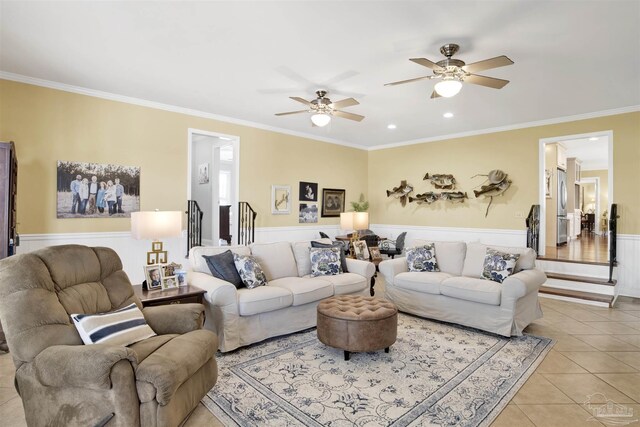 living room with a wainscoted wall, ceiling fan, crown molding, and light tile patterned floors