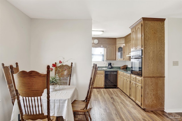 kitchen with dark countertops, black appliances, light wood-style flooring, and light brown cabinets