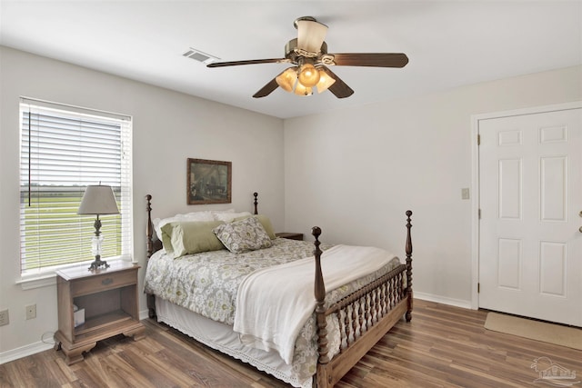bedroom featuring visible vents, baseboards, ceiling fan, and wood finished floors