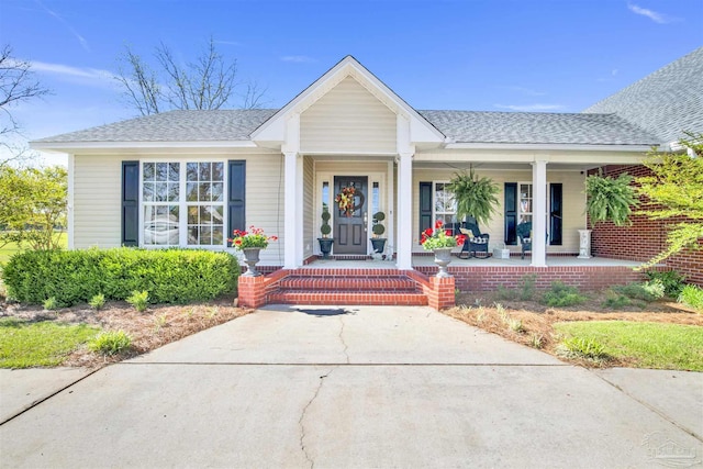 entrance to property with covered porch and roof with shingles
