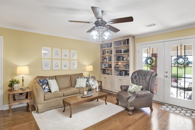 living room with a ceiling fan, wood finished floors, ornamental molding, and visible vents