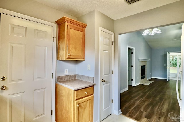 kitchen with a brick fireplace, baseboards, dark wood finished floors, light countertops, and a textured ceiling