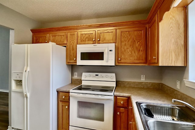 kitchen with a sink, white appliances, a textured ceiling, and brown cabinets