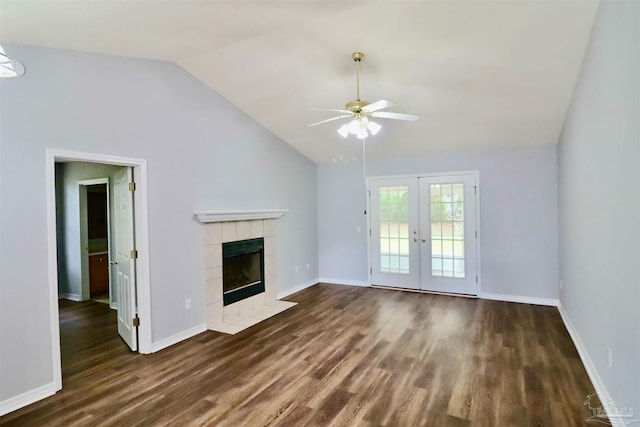 unfurnished living room with baseboards, a tiled fireplace, lofted ceiling, french doors, and dark wood-style floors