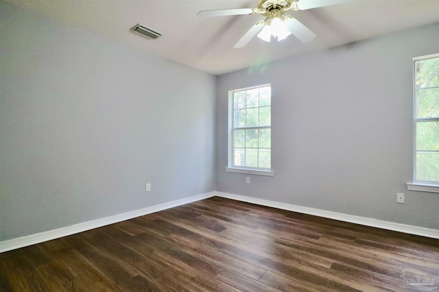 spare room with a wealth of natural light, visible vents, and dark wood finished floors