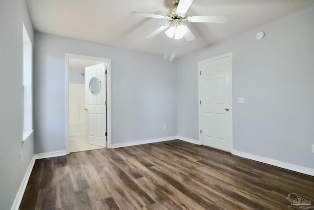 unfurnished bedroom with ensuite bathroom, baseboards, and wood finished floors