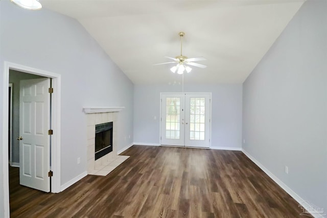 unfurnished living room with dark wood-type flooring, baseboards, lofted ceiling, a tile fireplace, and french doors