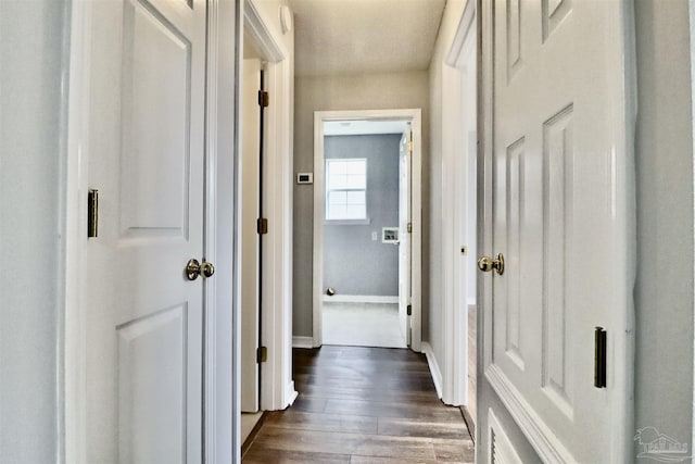 corridor with dark wood finished floors and baseboards