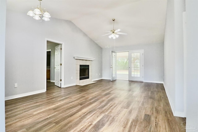 unfurnished living room featuring ceiling fan with notable chandelier, wood finished floors, a fireplace, and lofted ceiling