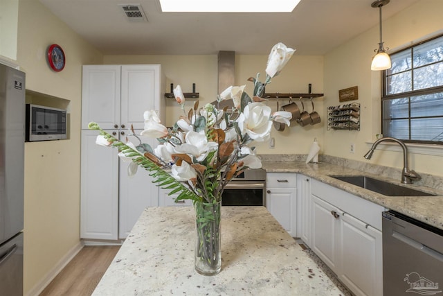 kitchen with visible vents, light wood-style flooring, a sink, white cabinetry, and stainless steel appliances