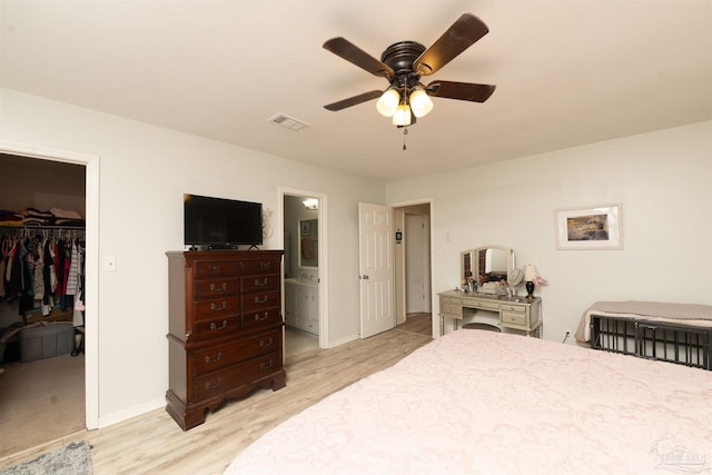 bedroom featuring visible vents, a walk in closet, baseboards, light wood-type flooring, and a closet