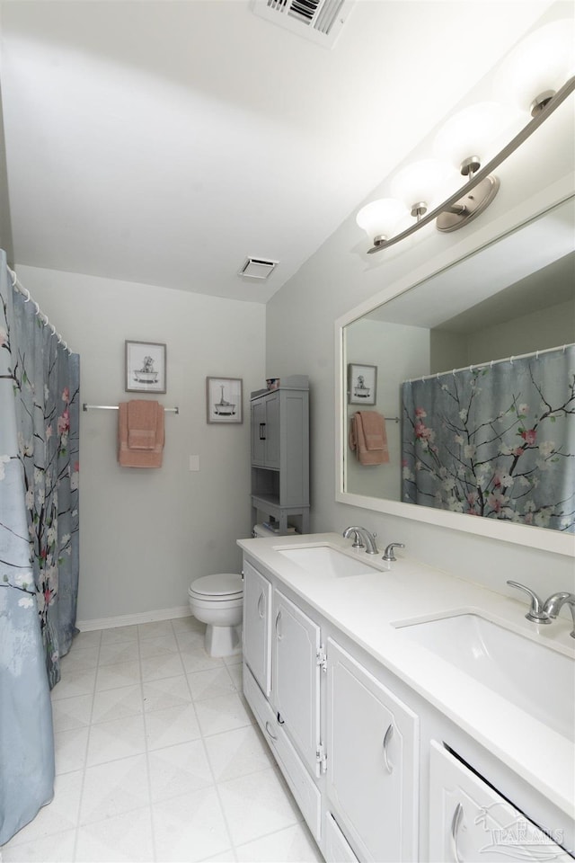 bathroom featuring toilet, a sink, double vanity, and visible vents