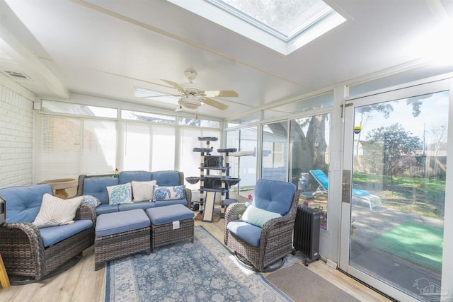 sunroom / solarium with a skylight, visible vents, radiator, and ceiling fan