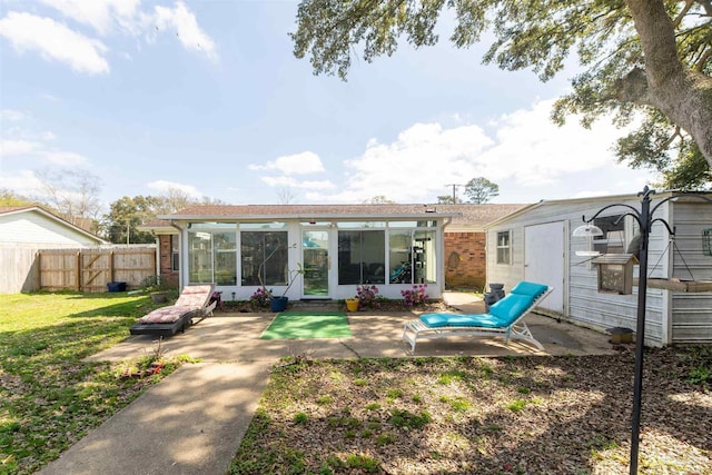 rear view of house featuring fence, a yard, a sunroom, a patio area, and brick siding