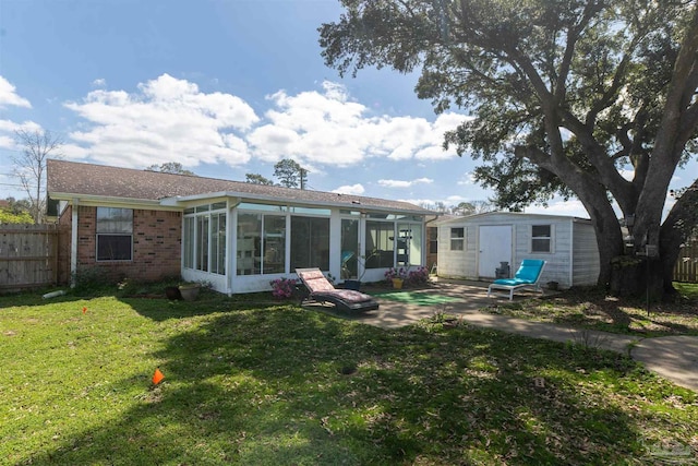 rear view of property featuring a yard, an outbuilding, fence, and a sunroom